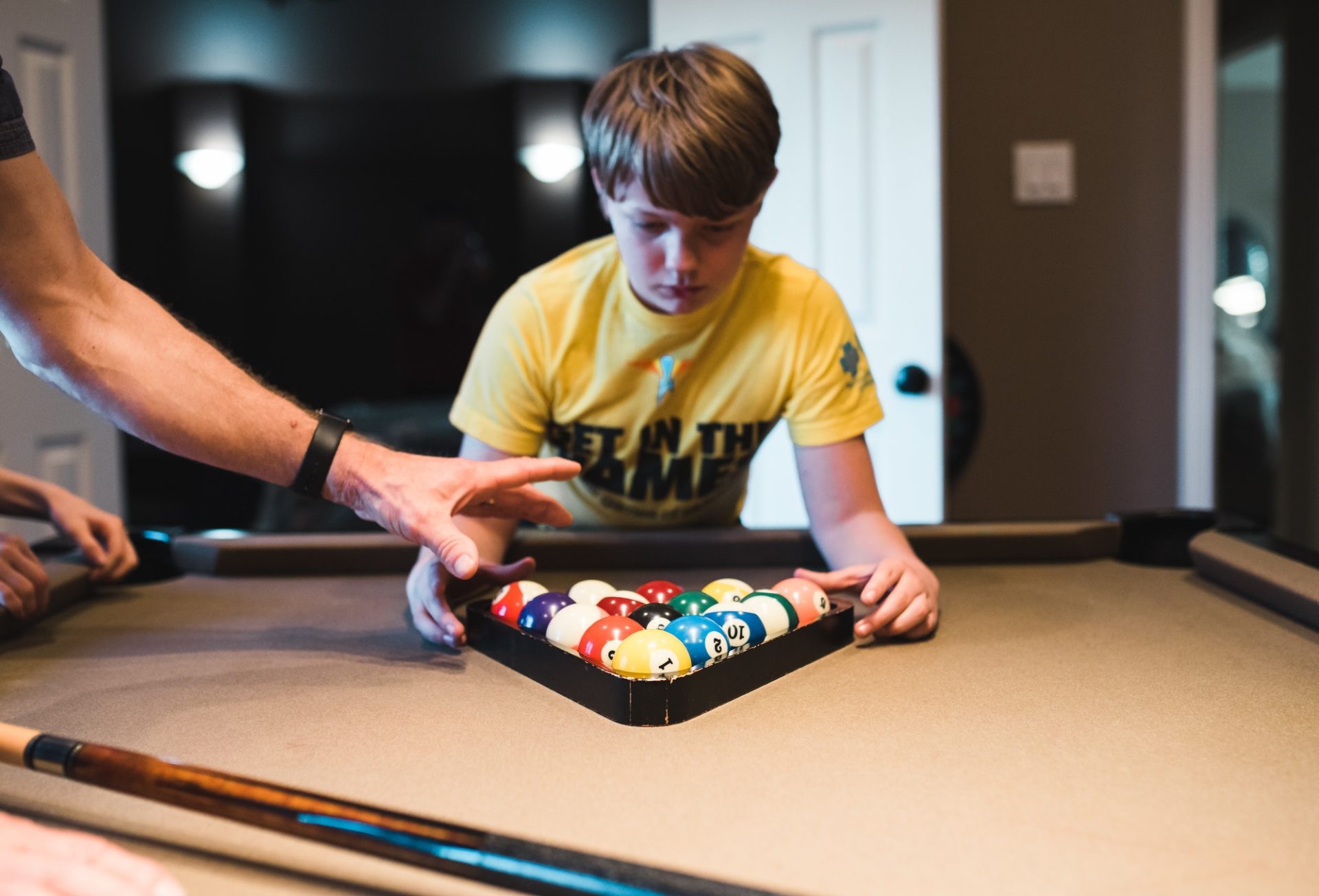 A child sets a rack for a game of pool